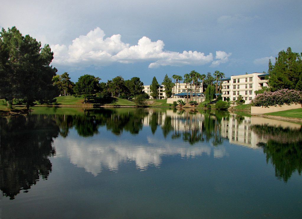 A lake with buildings in the background and trees.